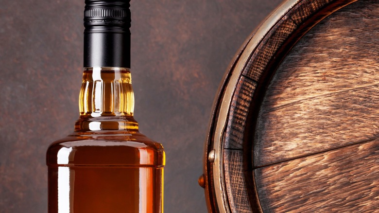 Unmarked bottle of bourbon and barrel