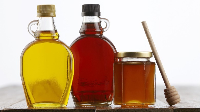 Agave, maple syrup, and honey sitting on a wooden table