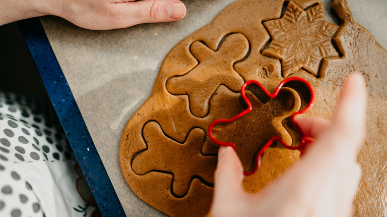 Person cutting cookies from a sheet of raw gingerbread dough