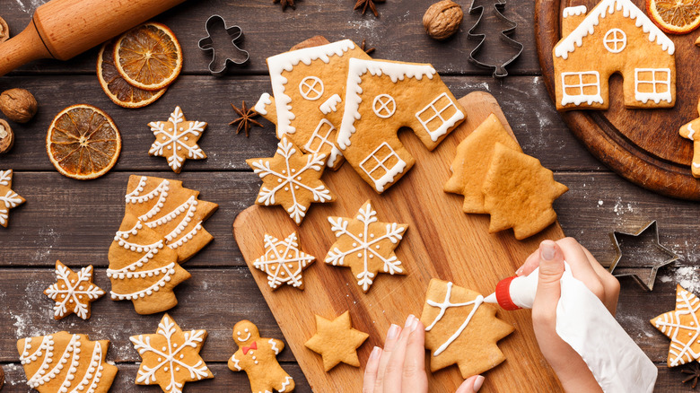 Icing being hand-piped onto festive gingerbread cookies