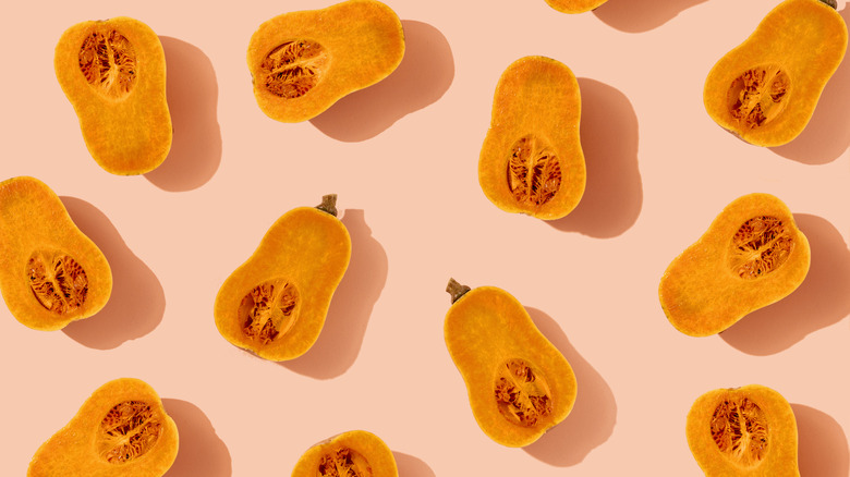 Sliced butternut squash halves on a pale pink background