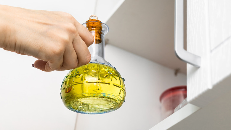 Placing jar of olive oil on cabinet shelf