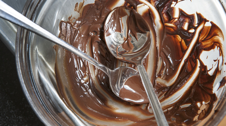 Glass bowl with melted chocolate and spoons