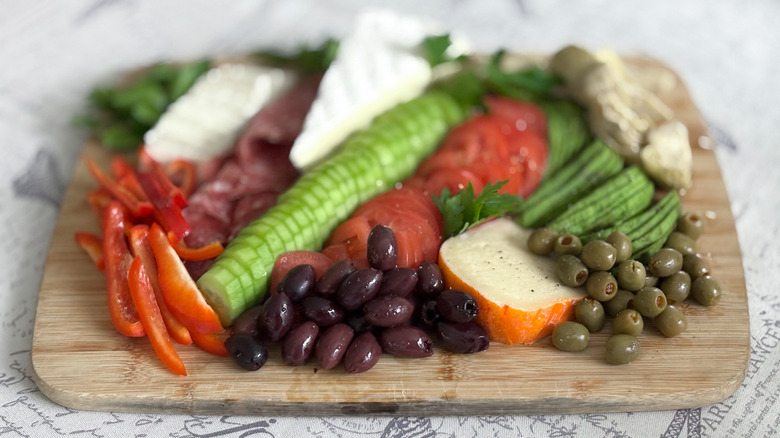 arrangement of vegetables, cheeses, and olives on board