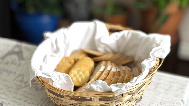 sliced bread and crackers in basket with towel