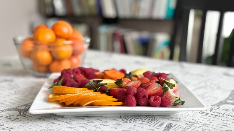 fruit plate with bowl of oranges in background