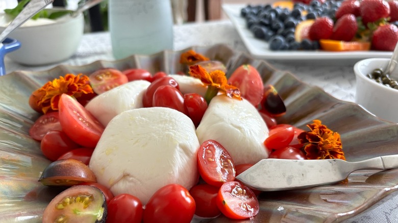 plate of burrata balls with cherry tomatoes and flowers