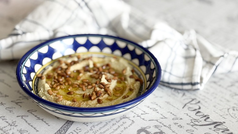 hummus with olive oil and pine nuts in Middle Eastern bowl