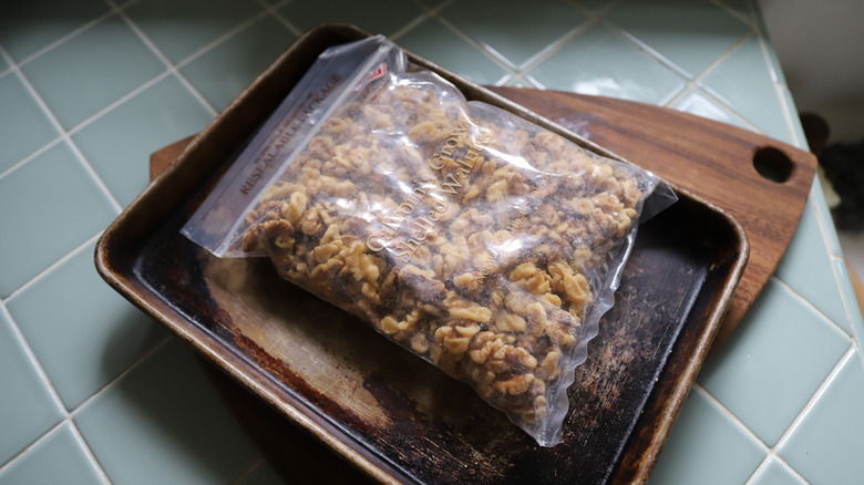 Walnuts in bag on top of metal pan and wooden tray