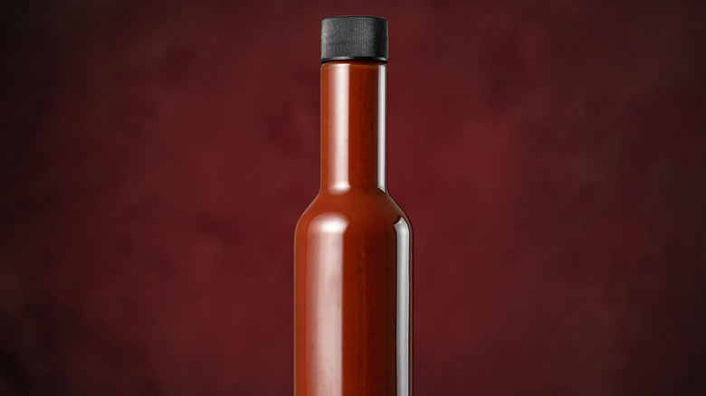 Bottle of hot sauce in front of a red background