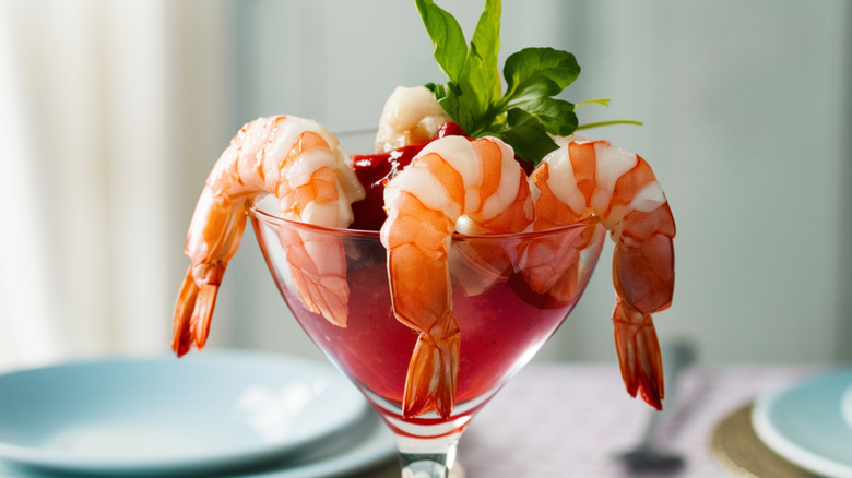 Shrimp in glass with cocktail sauce and fresh herbs