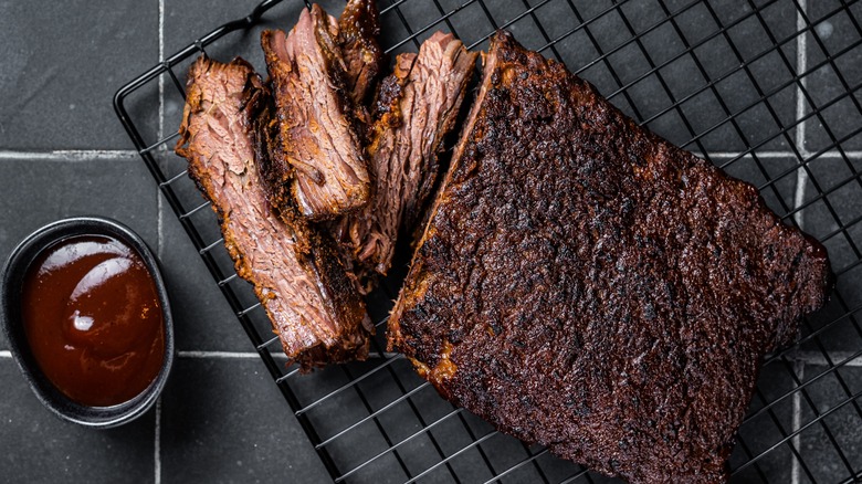 Sliced barbecue brisket with side of barbecue sauce