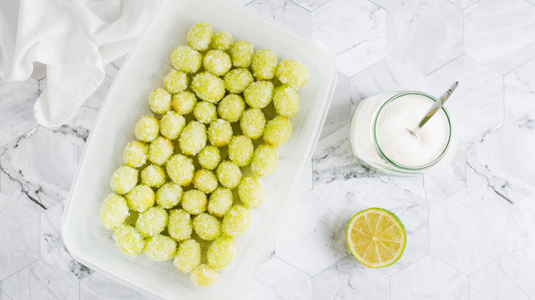 grapes coated in sugar in plastic container with sugar and cut lime