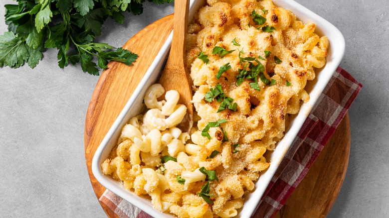 Macaroni and cheese in a casserole dish with wooden spoon