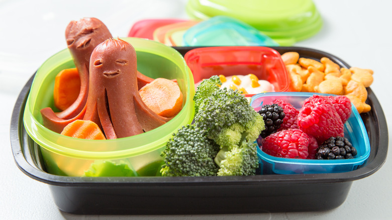 Hot dog octopuses in a lunch box with fruit and vegetables