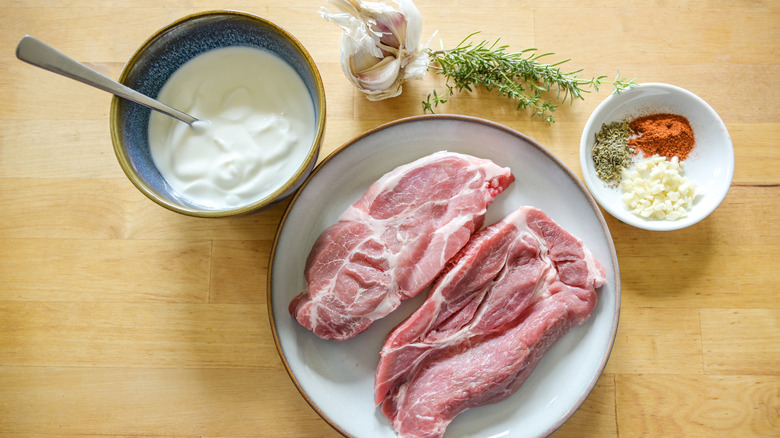 Raw meat on a plate with yogurt marinade ingredients