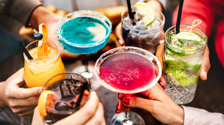 Group of people holding assorted colorful cocktails