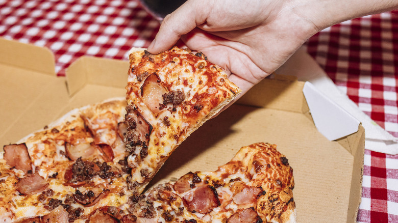 Someone taking a slice of fast food pizza