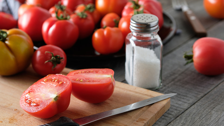 Salt and a sliced tomato on a cutting board