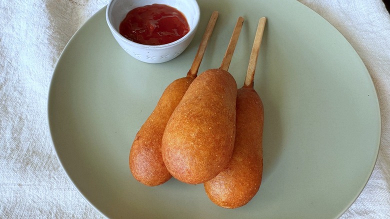 three corn dogs and ketchup