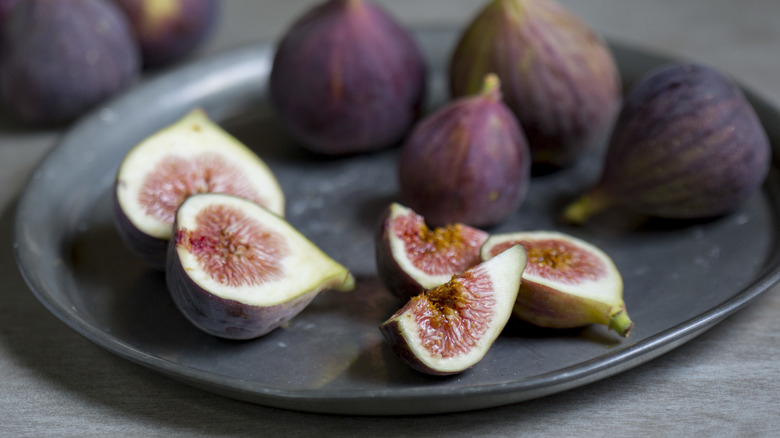 Fresh whole and sliced figs on a black plate