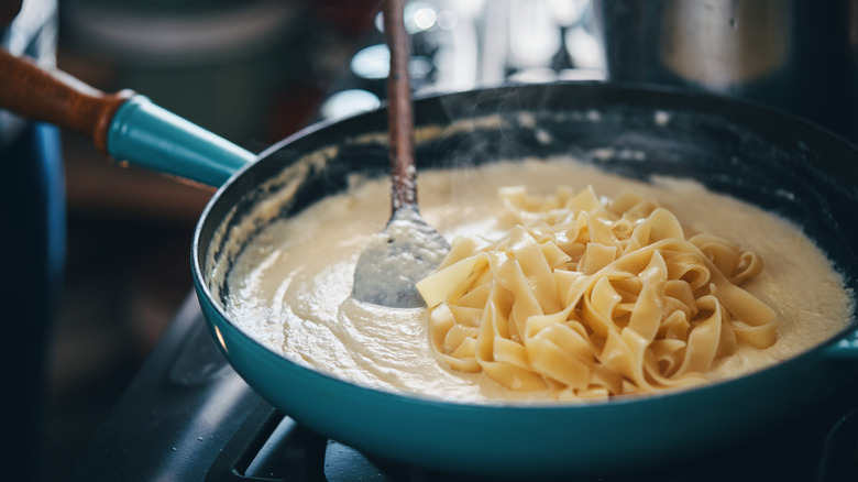 Stirring fettuccine into creamy Alfredo sauce