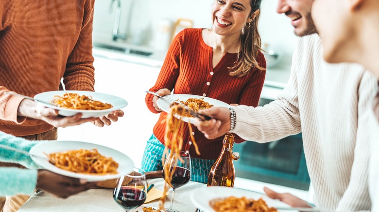 Smiling people eating spaghetti