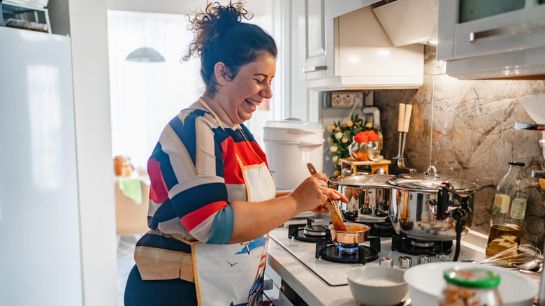 A woman happily cooking in her home kitchen