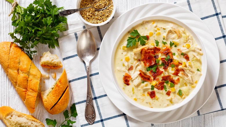 a bowl of chicken corn chowder with sliced French bread