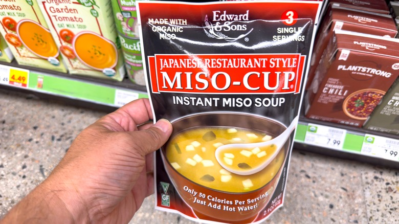 Hand holding a package of instant miso soup.