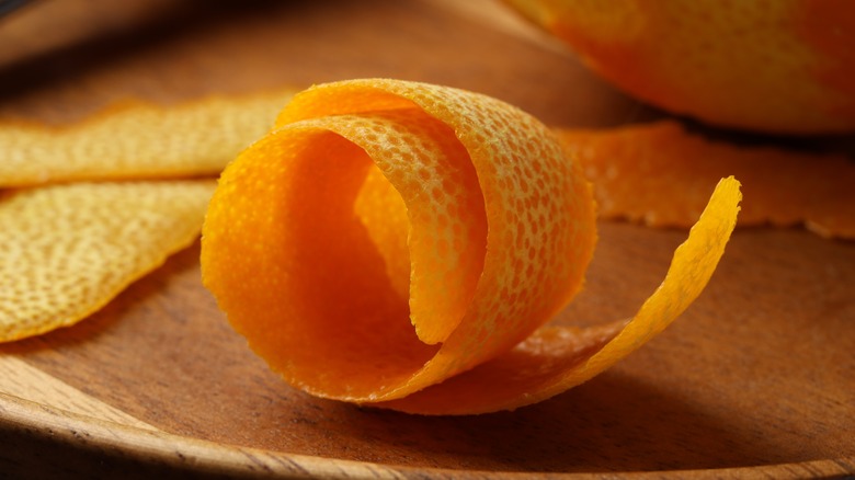 Fresh, curled orange peel on a wooden table