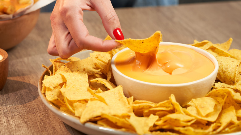 Hand dunking chip in cheese