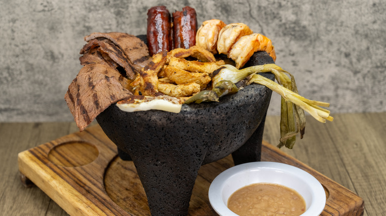 meat and vegetables served in molcajete on wooden board