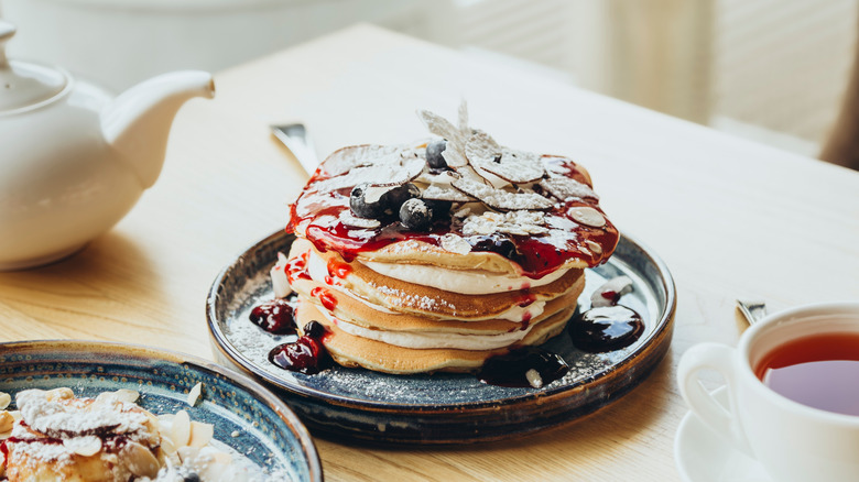 stack of pancakes with jam and powdered sugar