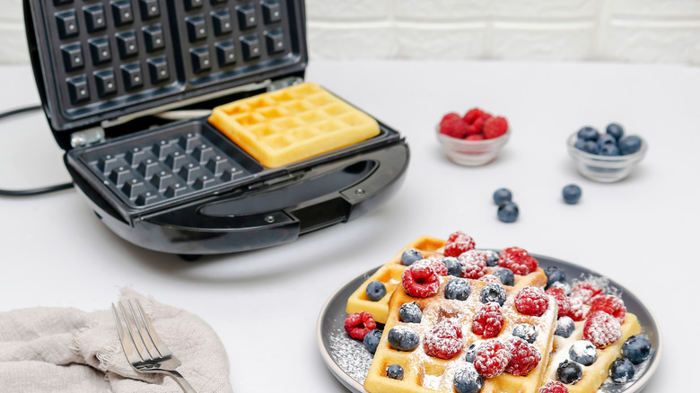 waffle iron with waffles covered in berries