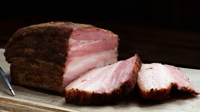 Pork brisket is sliced and sitting on a cutting board.