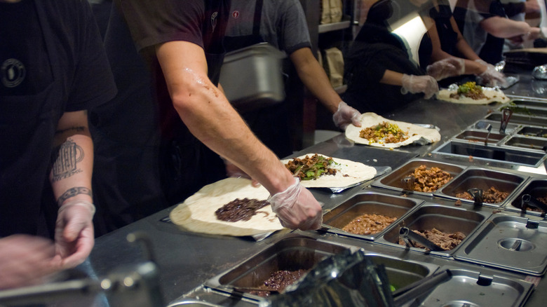 Hand working on Chipotle assembly line