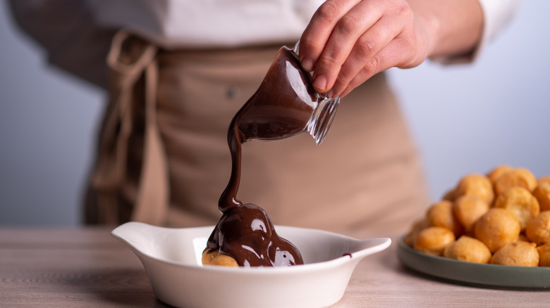 Pouring thick chocolate over profiteroles