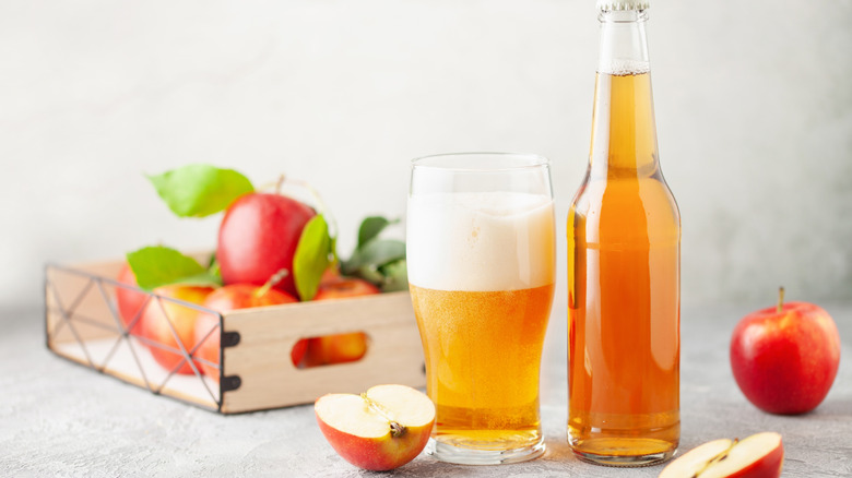 bottle and glass of hard cider with apples