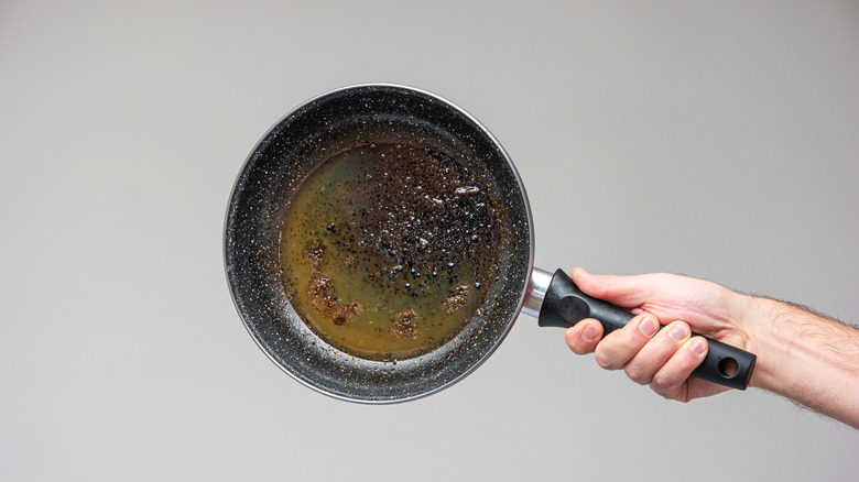 hand holding pan with burnt food