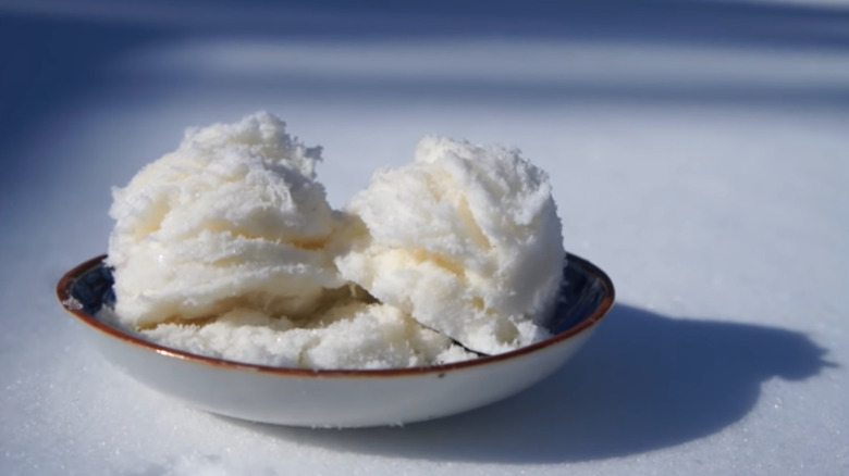 Two scoops of snow cream in a dish in the snow. 