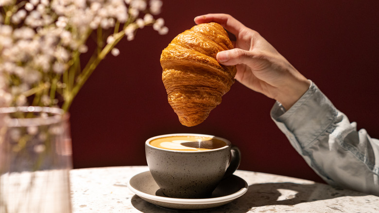 a croissant above a cup of cappuccino