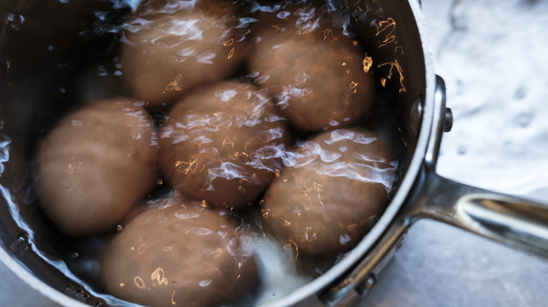 Several eggs submerged in water in a pot