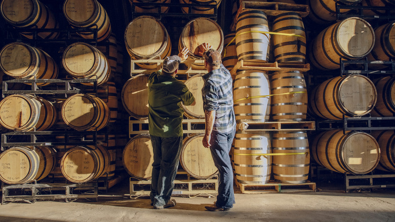 Brewmasters examine aging whiskey barrels