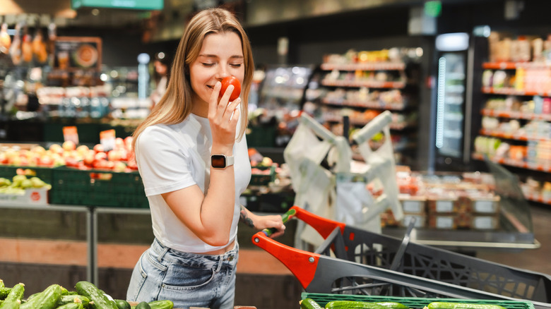 Woman smelling a tomato while grocery shopping