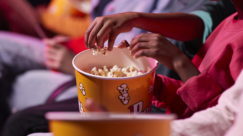 Reaching into popcorn bucket at the movies