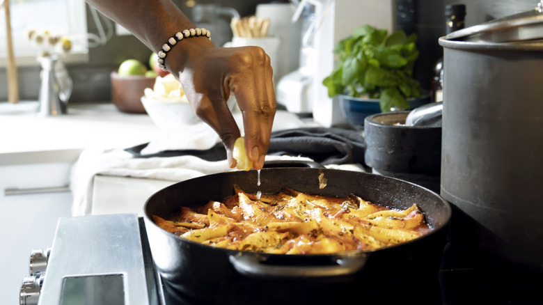 Squeezing lemon juice into a pan