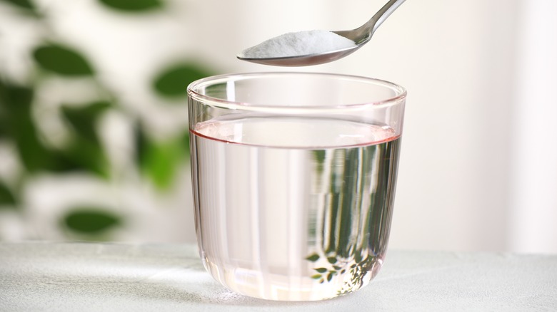 Spoon with baking soda over glass of water