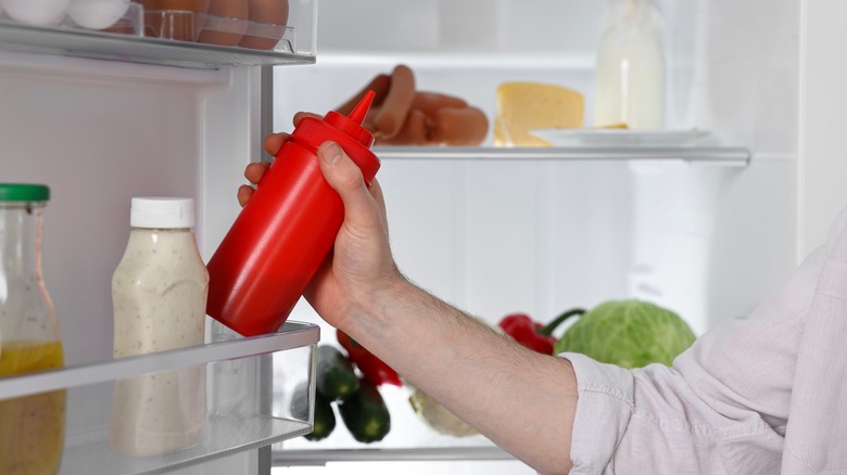 Person grabbing ketchup from the fridge