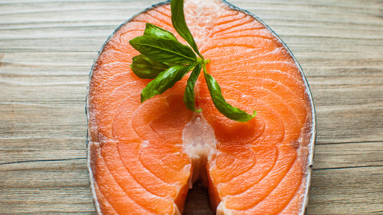 close up of raw salmon steak topped with fresh herb